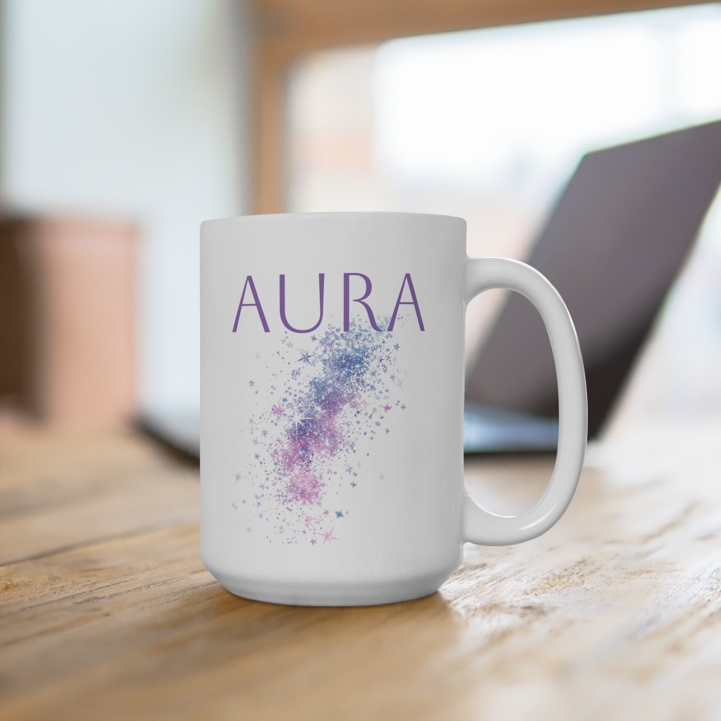 White ceramic aura mug with purple galaxy sparkle design on wooden desk beside laptop, handle right